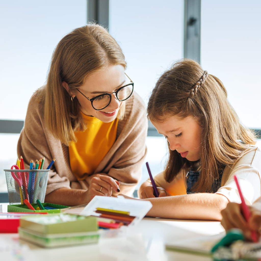 Eine Lehrerin sitzt neben einem kleinen Mädchen